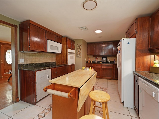 kitchen featuring backsplash, white appliances, and light tile patterned flooring