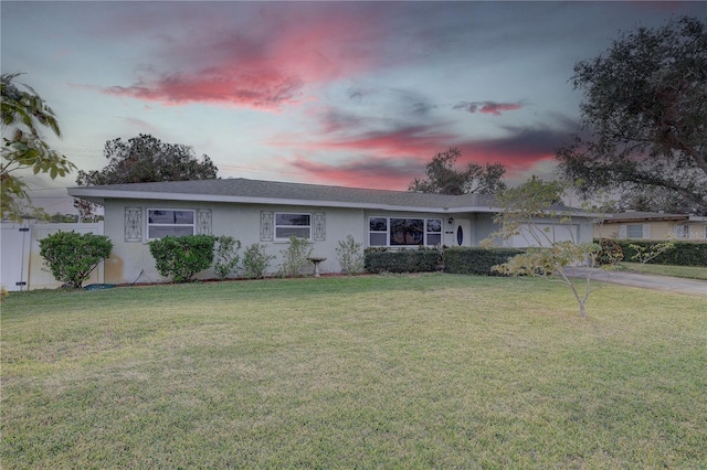 ranch-style home featuring a lawn and a garage