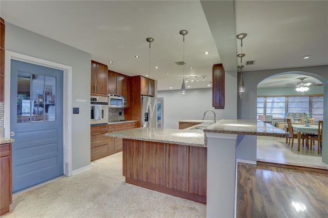 kitchen featuring backsplash, stainless steel appliances, ceiling fan, sink, and pendant lighting