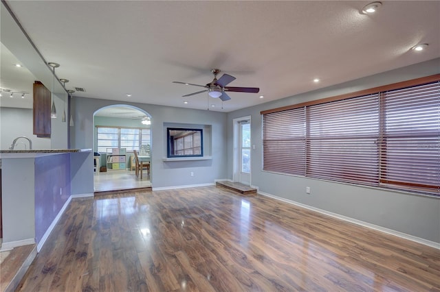 unfurnished living room featuring ceiling fan, sink, wood-type flooring, and a textured ceiling