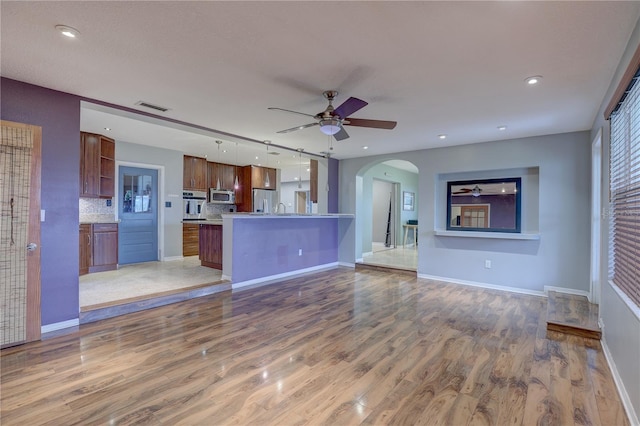 unfurnished living room featuring hardwood / wood-style flooring, ceiling fan, and sink