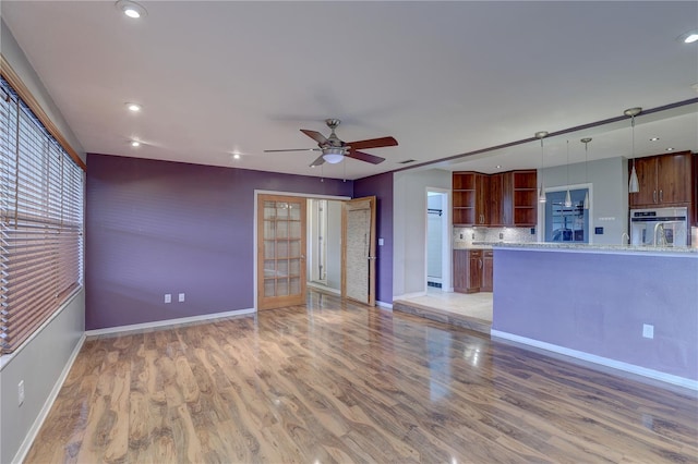 unfurnished living room with ceiling fan, hardwood / wood-style floors, and french doors