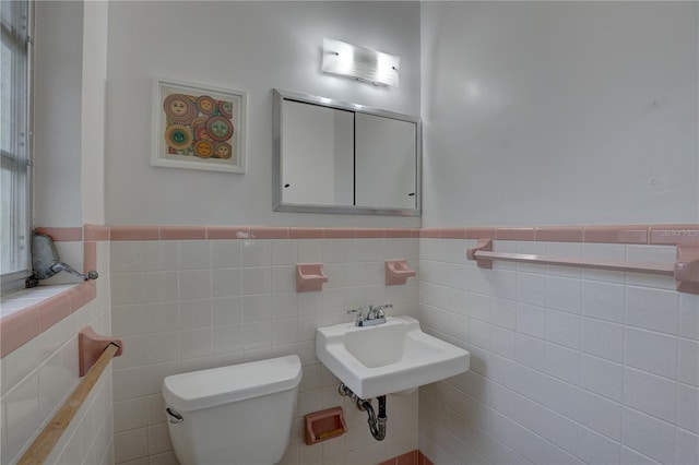 bathroom featuring toilet, tile walls, and sink