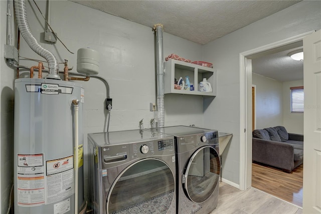 laundry area with a textured ceiling, light wood-type flooring, gas water heater, and independent washer and dryer