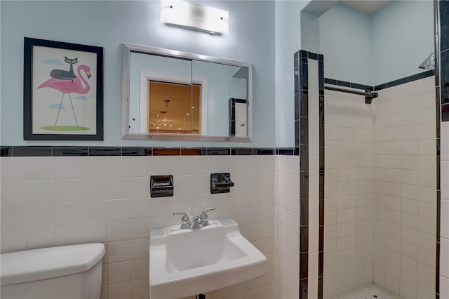 bathroom with a tile shower, sink, an AC wall unit, tile walls, and toilet