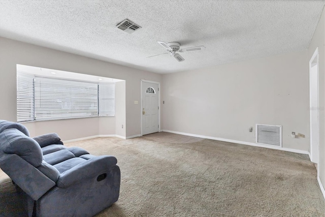 sitting room featuring ceiling fan, light colored carpet, and a textured ceiling