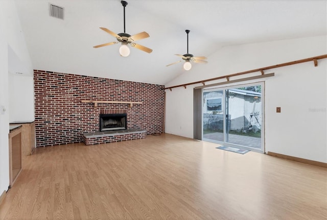 unfurnished living room featuring lofted ceiling, ceiling fan, a brick fireplace, light hardwood / wood-style floors, and brick wall