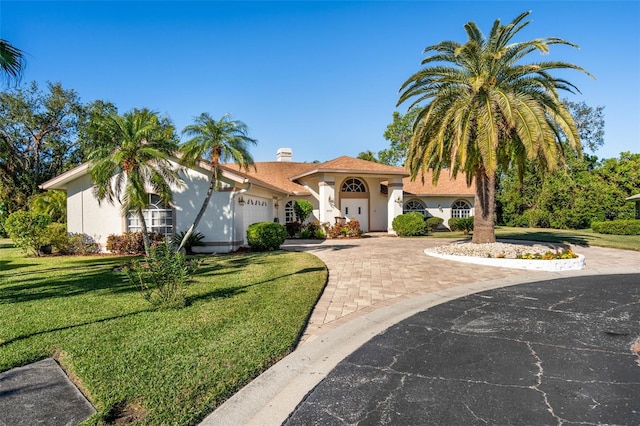 mediterranean / spanish-style home featuring a front yard and a garage