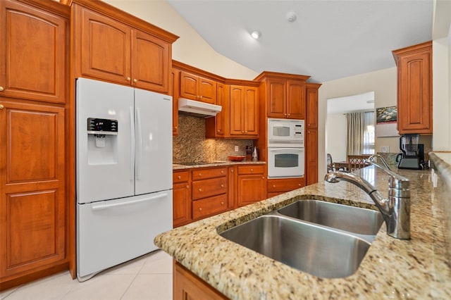 kitchen featuring white appliances, vaulted ceiling, light stone counters, sink, and backsplash