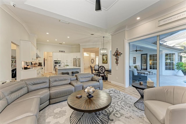 living room with ceiling fan with notable chandelier and light hardwood / wood-style flooring