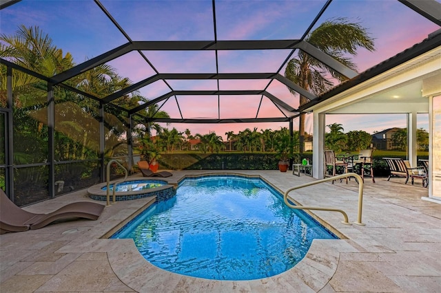 pool at dusk featuring glass enclosure, a patio area, and an in ground hot tub