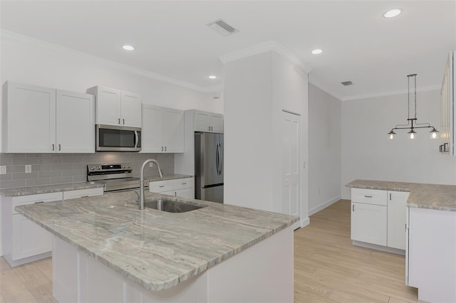 kitchen featuring appliances with stainless steel finishes, decorative light fixtures, sink, and a center island with sink