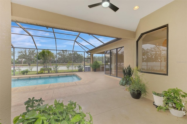 view of swimming pool featuring ceiling fan, glass enclosure, and a patio area