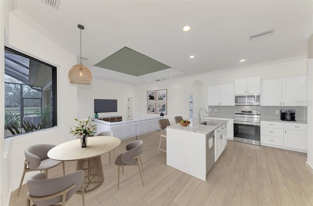 kitchen featuring decorative light fixtures, sink, white cabinets, stainless steel appliances, and light stone countertops