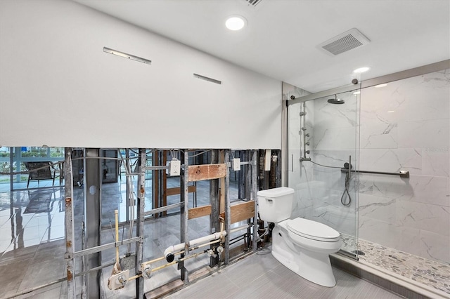 bathroom with a marble finish shower, visible vents, and toilet