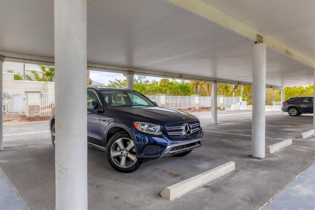 view of parking / parking lot featuring a parking deck and fence