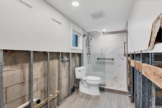 full bathroom featuring toilet, a marble finish shower, and visible vents