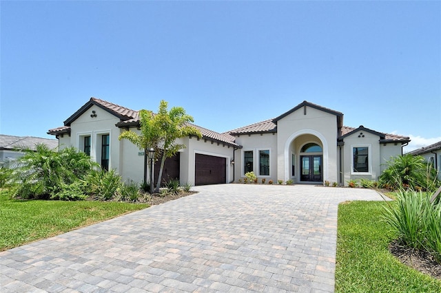 10612 Nicklaus Ct, Englewood, FL 34223 - mediterranean / spanish-style house featuring french doors, stucco siding, an attached garage, decorative driveway, and a tiled roof