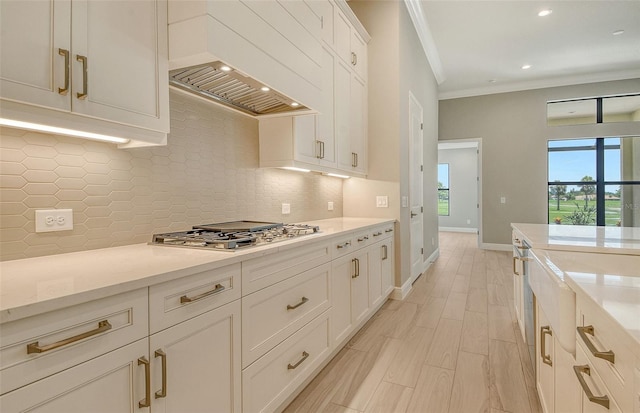 10612 Nicklaus Ct, Englewood, FL 34223 - kitchen featuring crown molding, stainless steel gas stovetop, backsplash, baseboards, and white cabinets