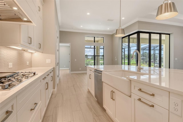 10612 Nicklaus Ct, Englewood, FL 34223 - kitchen featuring appliances with stainless steel finishes, under cabinet range hood, backsplash, white cabinets, and pendant lighting
