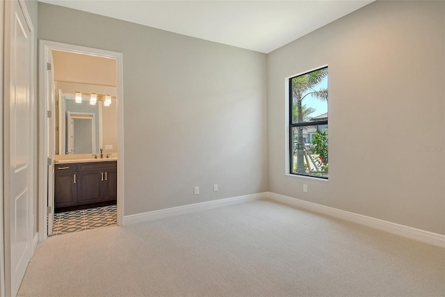 10612 Nicklaus Ct, Englewood, FL 34223 - unfurnished bedroom with light carpet, baseboards, ensuite bath, and a sink