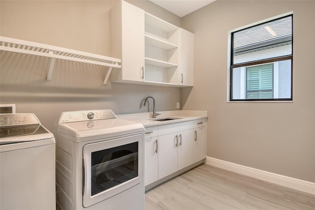 10612 Nicklaus Ct, Englewood, FL 34223 - laundry area with washing machine and clothes dryer, light wood-style flooring, baseboards, and cabinet space