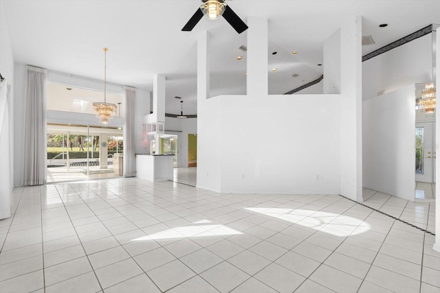 unfurnished living room with light tile patterned flooring, a high ceiling, and ceiling fan with notable chandelier