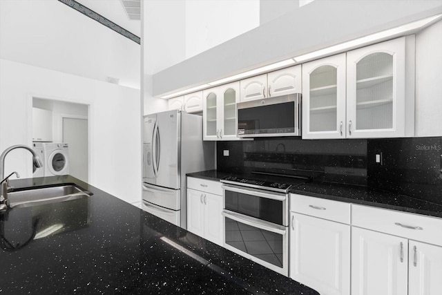 kitchen featuring washer and clothes dryer, white cabinets, appliances with stainless steel finishes, and tasteful backsplash