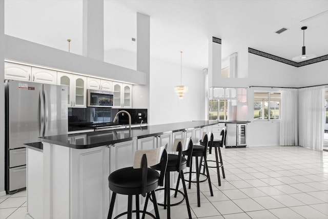 kitchen featuring appliances with stainless steel finishes, beverage cooler, light tile patterned floors, pendant lighting, and white cabinets