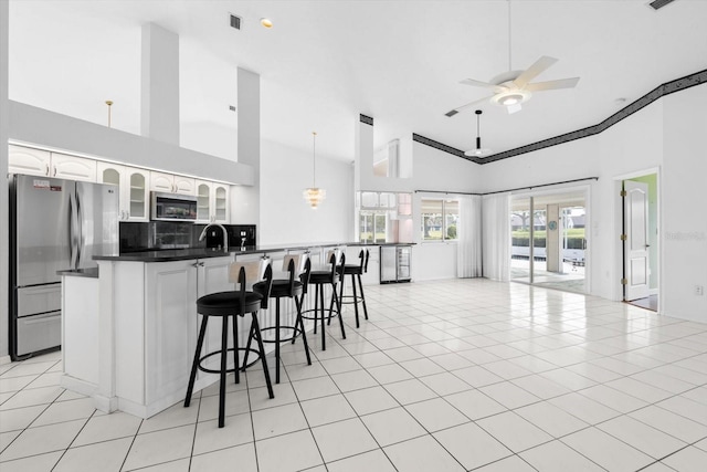 kitchen featuring ceiling fan, light tile patterned floors, a breakfast bar, white cabinets, and appliances with stainless steel finishes