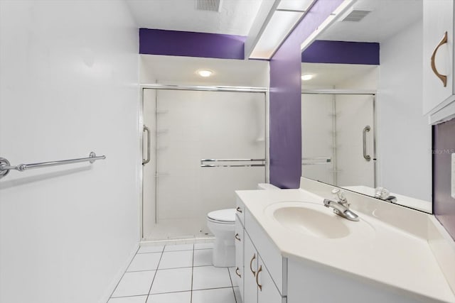 bathroom featuring toilet, vanity, tile patterned floors, and a shower with shower door