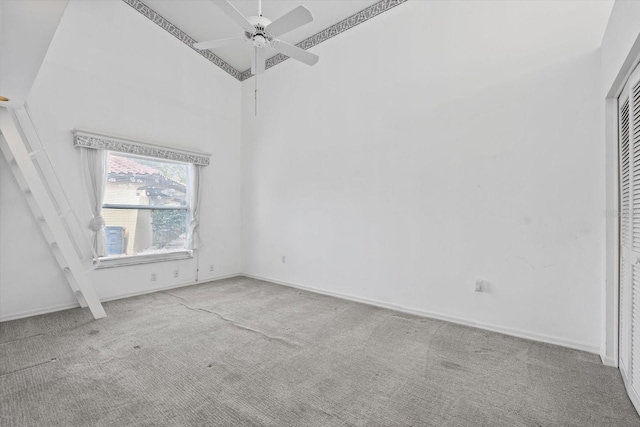 carpeted empty room with ceiling fan and high vaulted ceiling