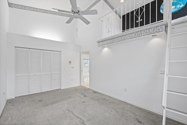 interior space featuring ceiling fan, a towering ceiling, and light carpet