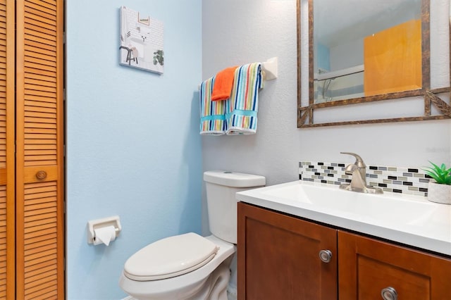 bathroom with backsplash, vanity, and toilet