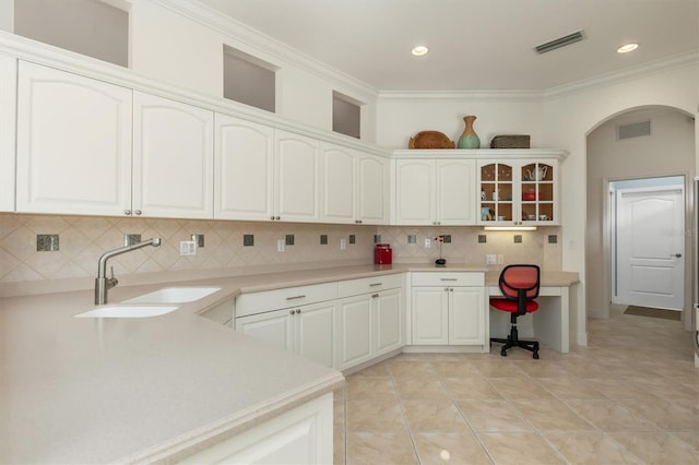 kitchen with backsplash, white cabinets, sink, ornamental molding, and light tile patterned floors