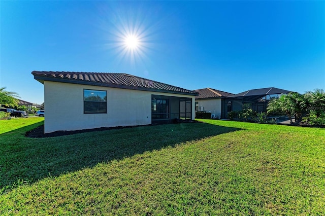 back of house featuring a lanai and a yard