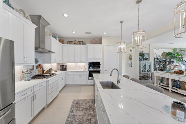 kitchen featuring backsplash, stainless steel appliances, wall chimney range hood, sink, and pendant lighting