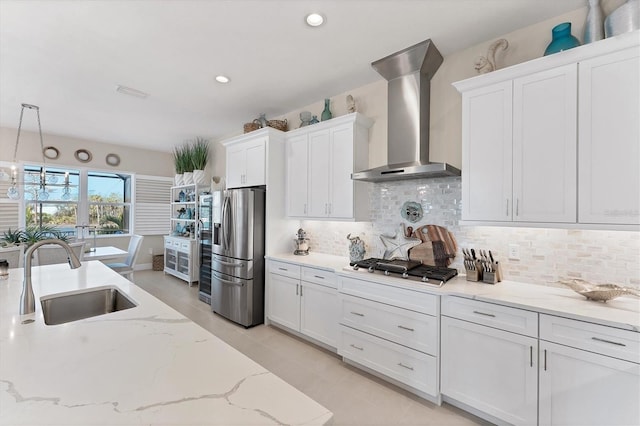 kitchen with wall chimney exhaust hood, stainless steel appliances, sink, pendant lighting, and white cabinets