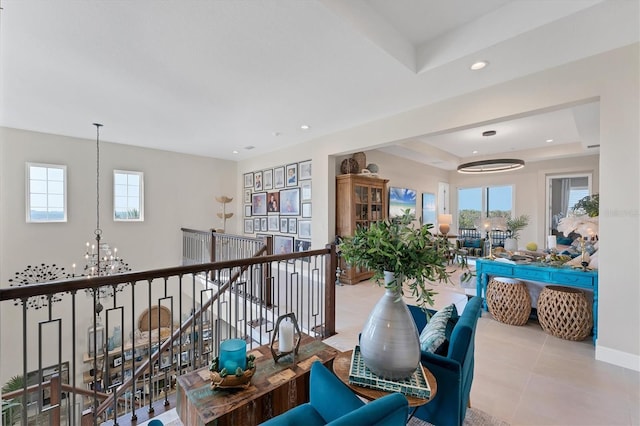 hall featuring light tile patterned floors, a tray ceiling, and plenty of natural light