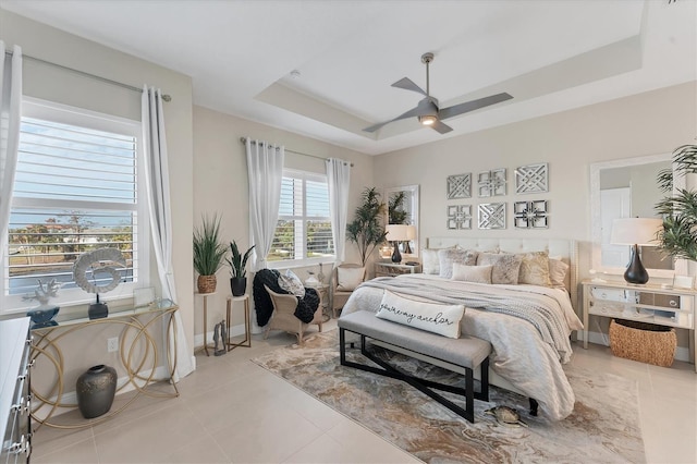 bedroom with ceiling fan, a raised ceiling, and light tile patterned floors