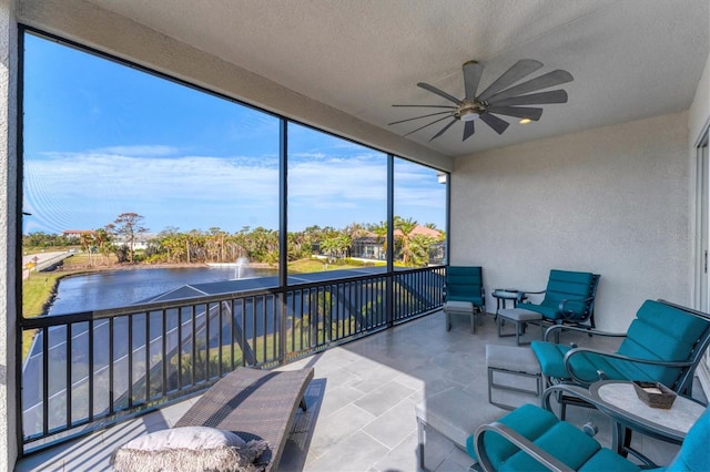 sunroom with ceiling fan and a water view