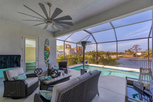 view of patio / terrace featuring a lanai, an outdoor living space, ceiling fan, a water view, and a fenced in pool