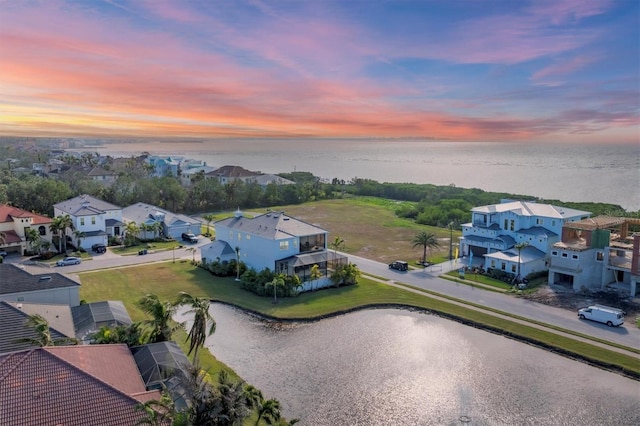 aerial view at dusk featuring a water view