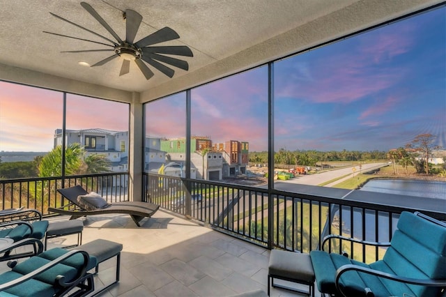 sunroom / solarium with a water view and ceiling fan