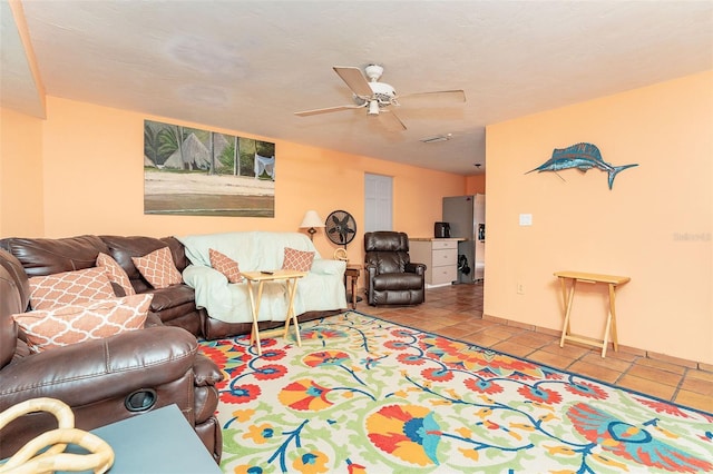 living room with ceiling fan, light tile patterned flooring, and a textured ceiling