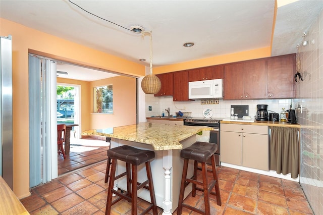 kitchen with backsplash, a breakfast bar, hanging light fixtures, and stainless steel range with electric stovetop