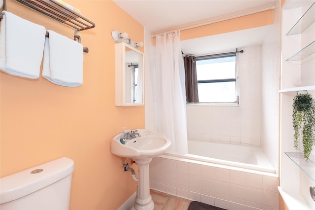 bathroom featuring toilet and shower / tub combo with curtain