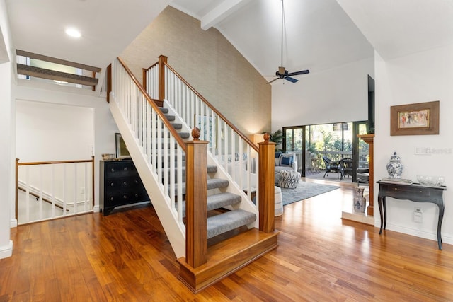 staircase featuring ceiling fan, beamed ceiling, high vaulted ceiling, and wood-type flooring