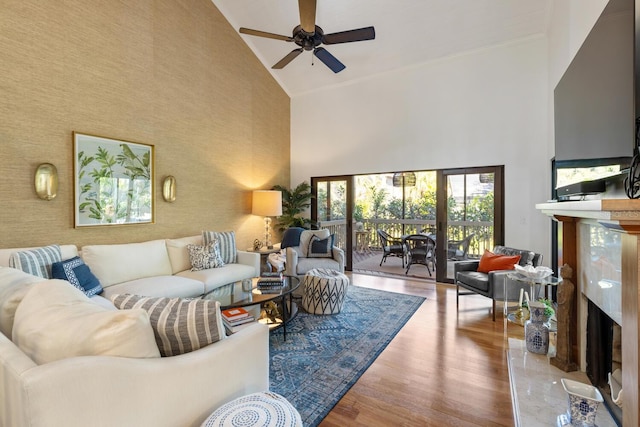 living room featuring a high end fireplace, light hardwood / wood-style flooring, high vaulted ceiling, and ceiling fan