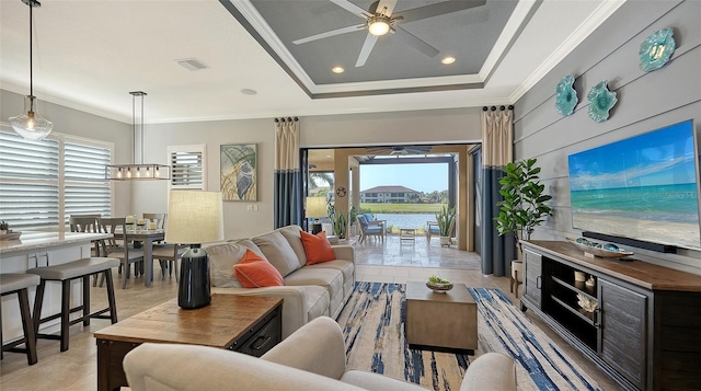 living room featuring ceiling fan, a raised ceiling, light tile patterned floors, and crown molding